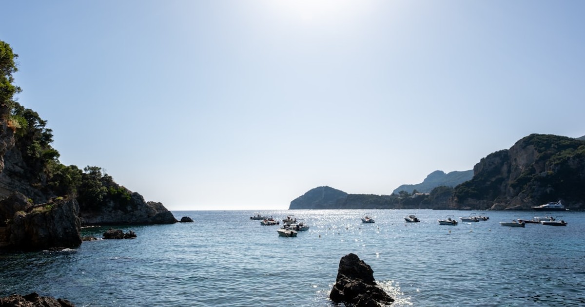 A classic sailing yacht cruising on a broad reach in Corfu with a picturesque shoreline in the distance