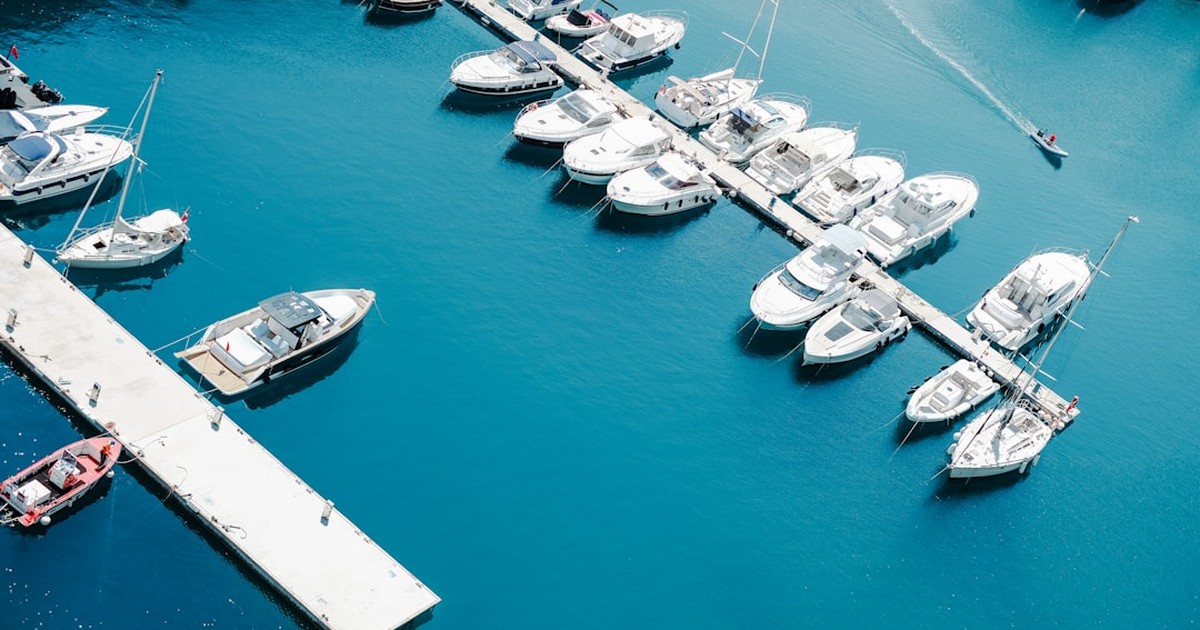 Rows of modern charter yachts and catamarans berthed at Gouvia Marina in Corfu during golden hour