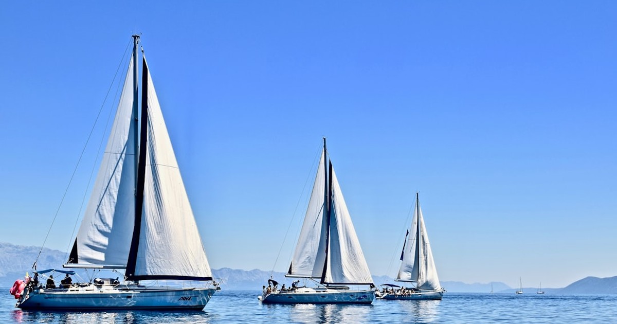A sailing catamaran anchoring in a pristine bay in Corsica under a clear sky