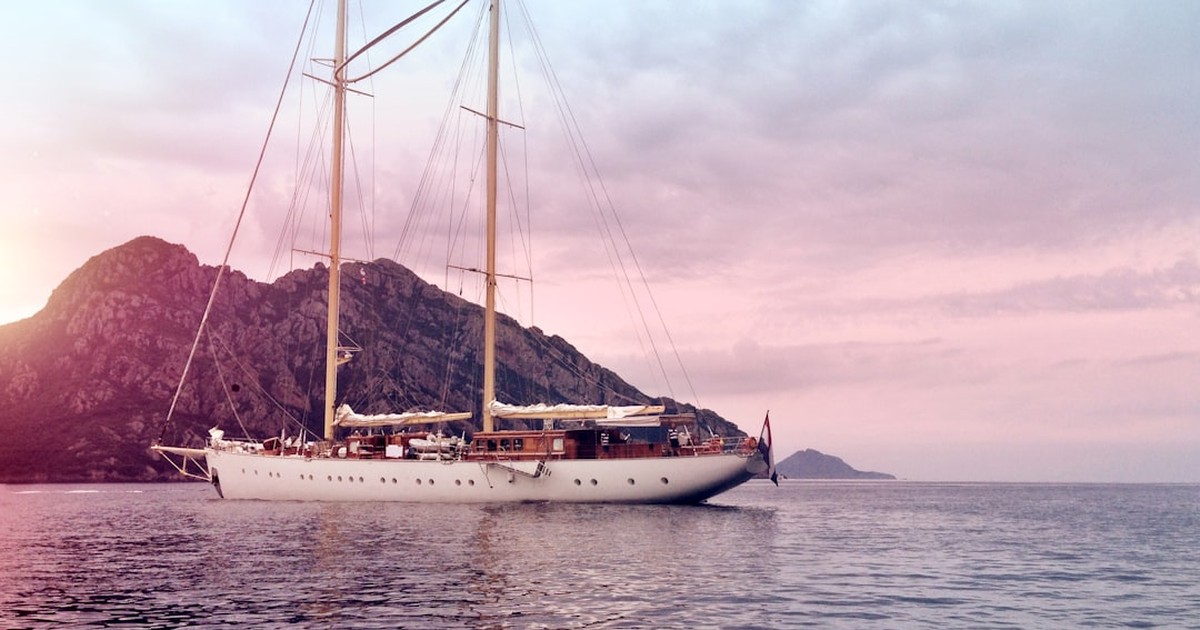 A classic sailing yacht cruising along the steep granite cliffs of Corsica near Bonifacio