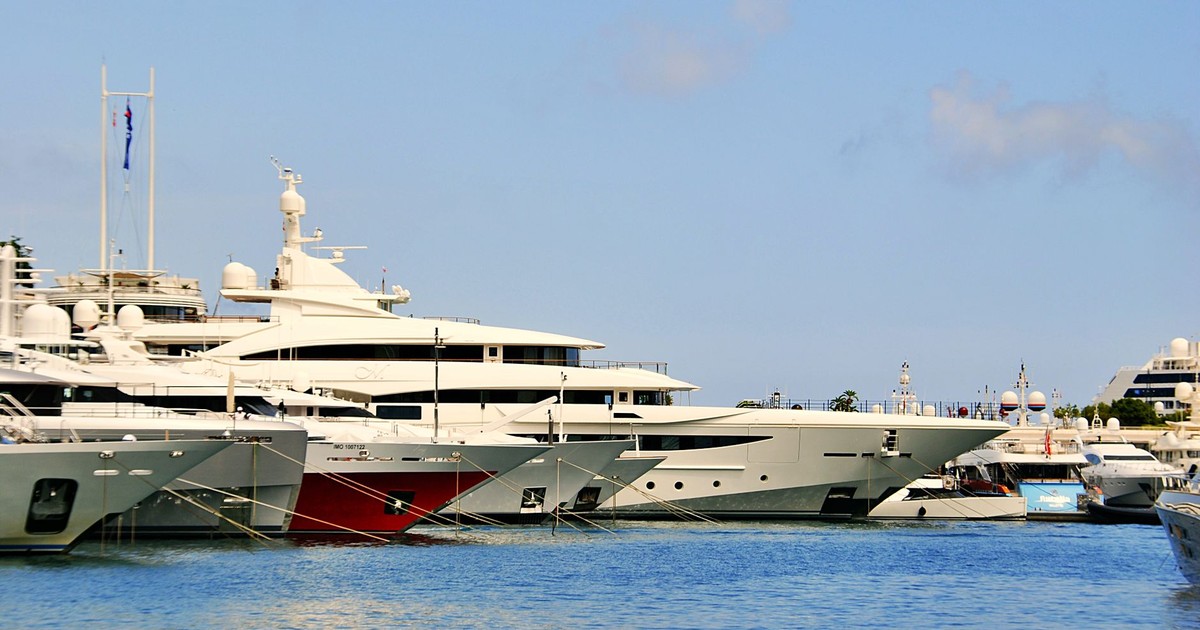 A row of modern charter catamarans berthed at Eden Island Marina in Mahé, Seychelles, with the granite hillside of the main island visible in the late afternoon sun